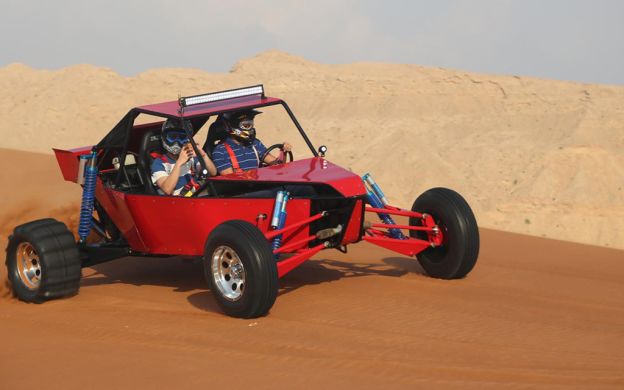Dynamic Duo on Buggy Ride in Dubai Desert - Two passengers embarcing advnture, creating lasting memories on a exhilarating desert buggy experience.